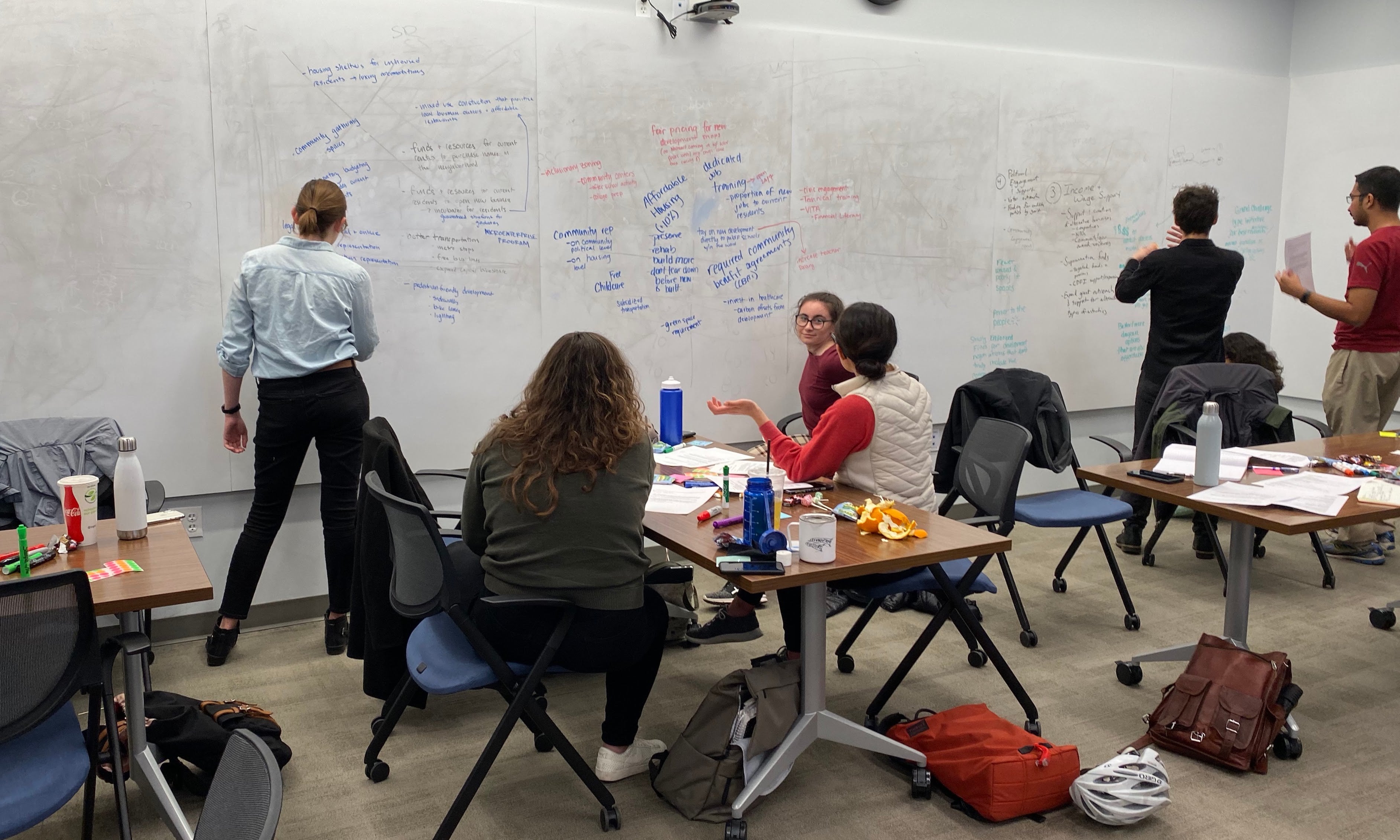 Students working in the community - seated at a table and writing items on a board