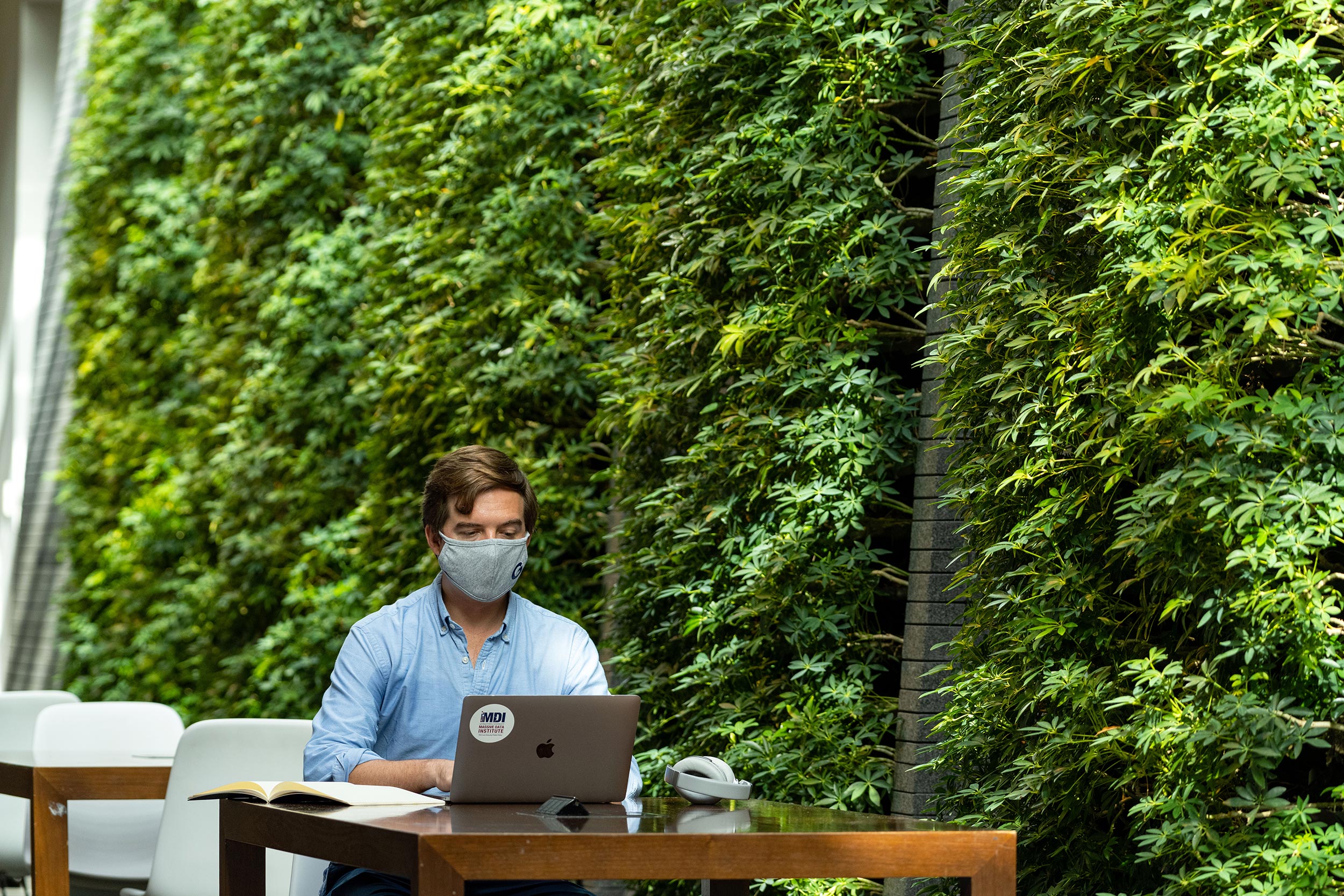 Employee wearing a mask sitting at a desk in the student center