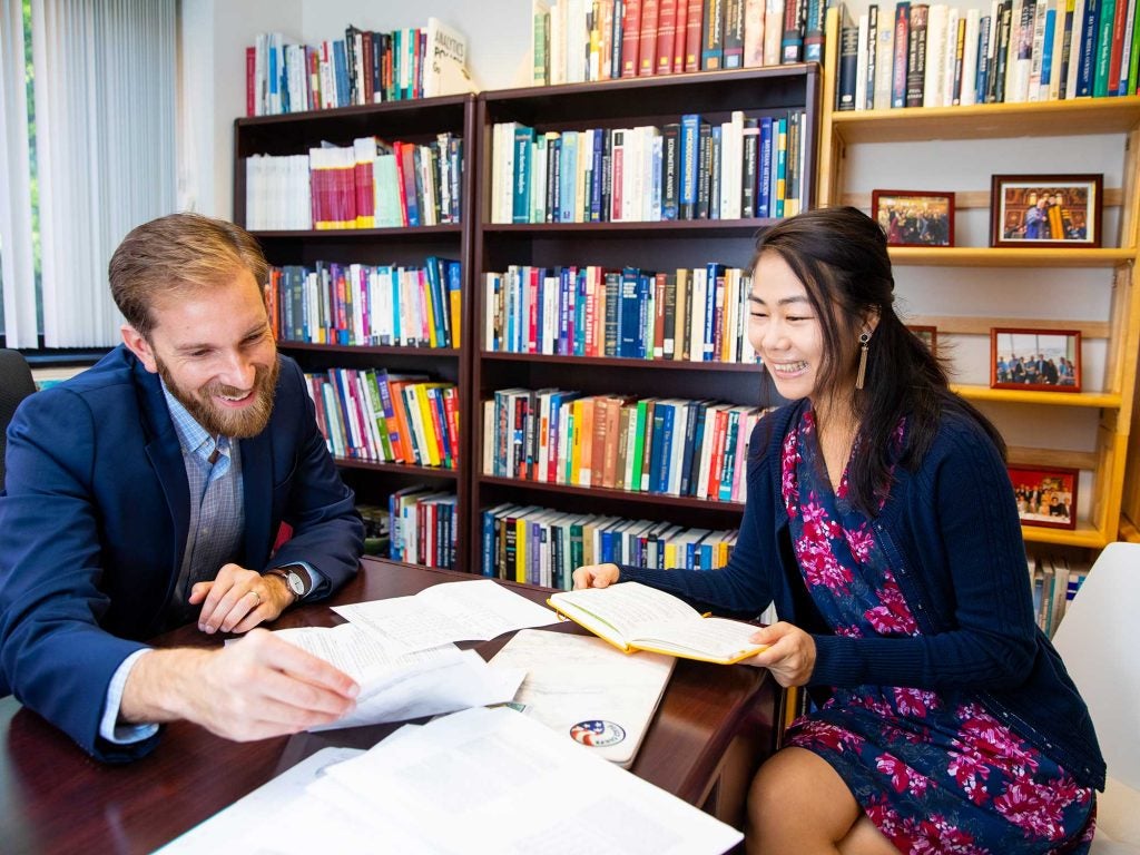 Professor Ladd & Frances Chen sitting around a small desk looking a papers