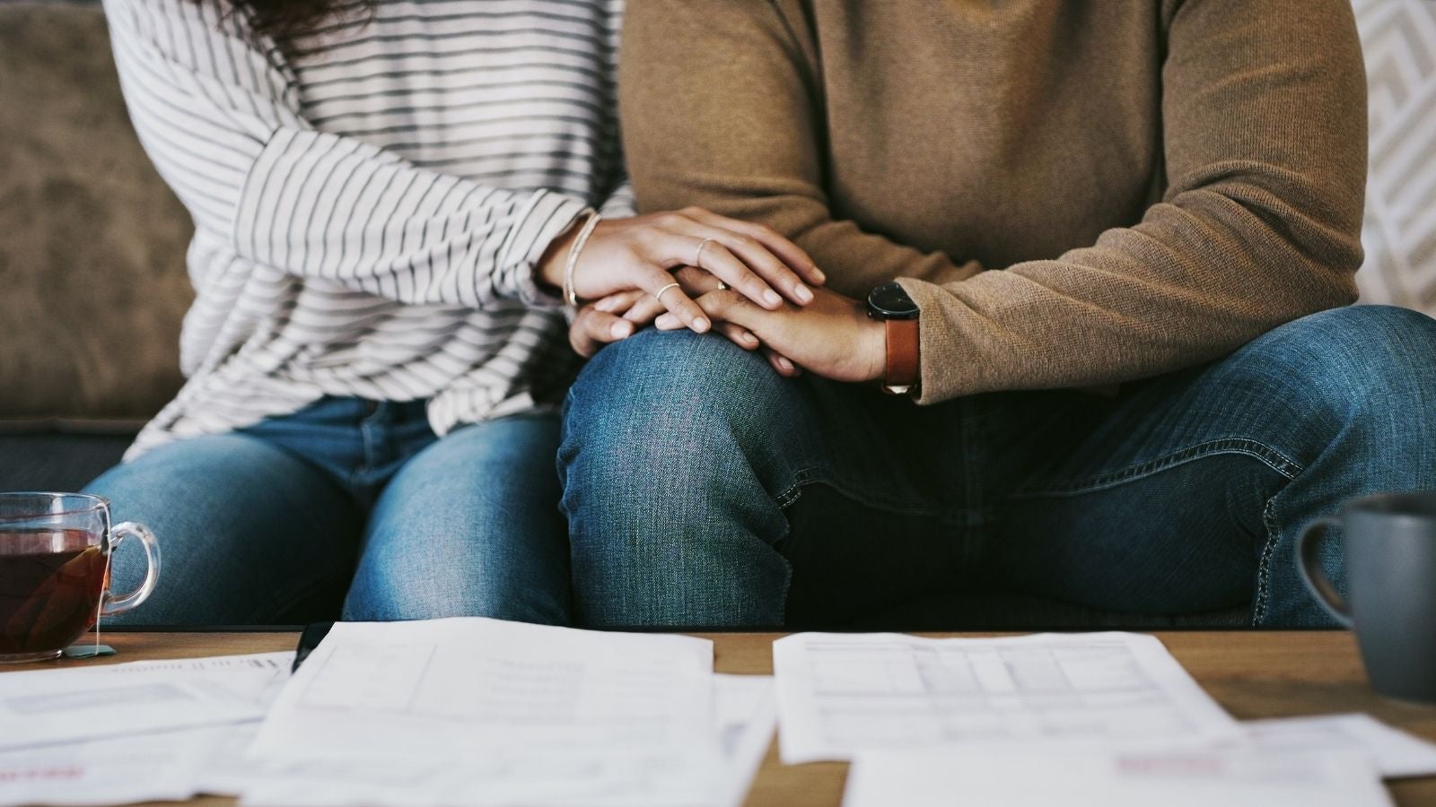 people holding hands while looking at papers