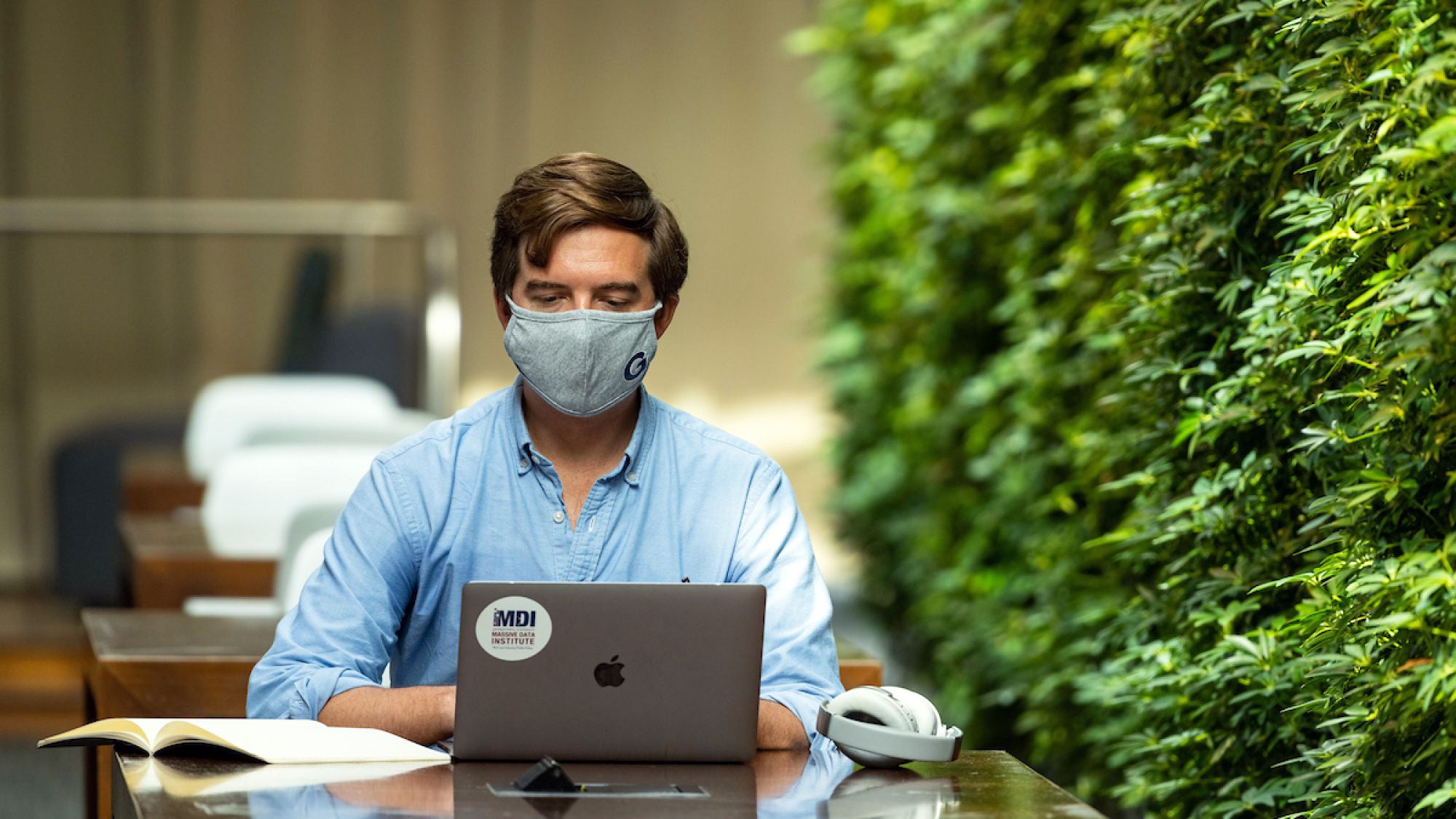 Employee wearing a mask sitting at a desk in the student center