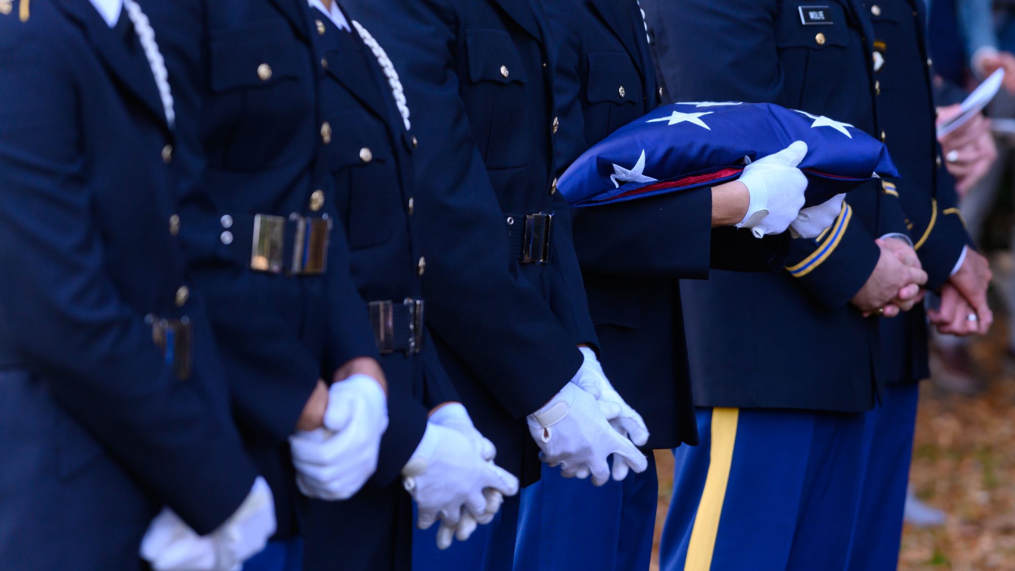 Service members holding folded American flag