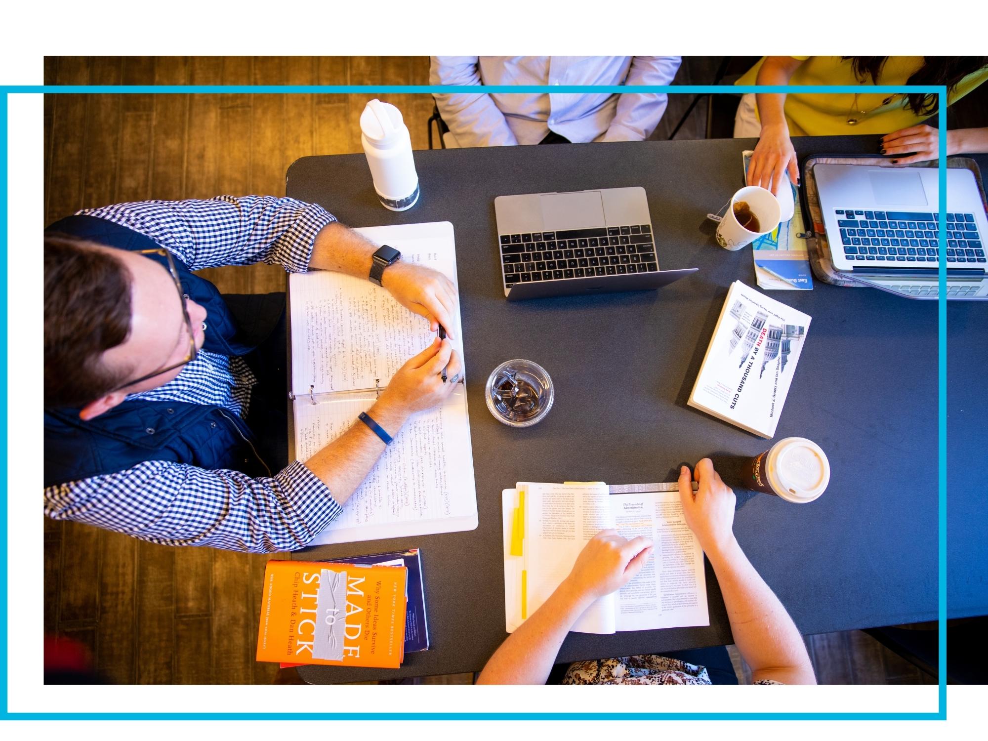 Overhead image of a desk with notebooks and laptops