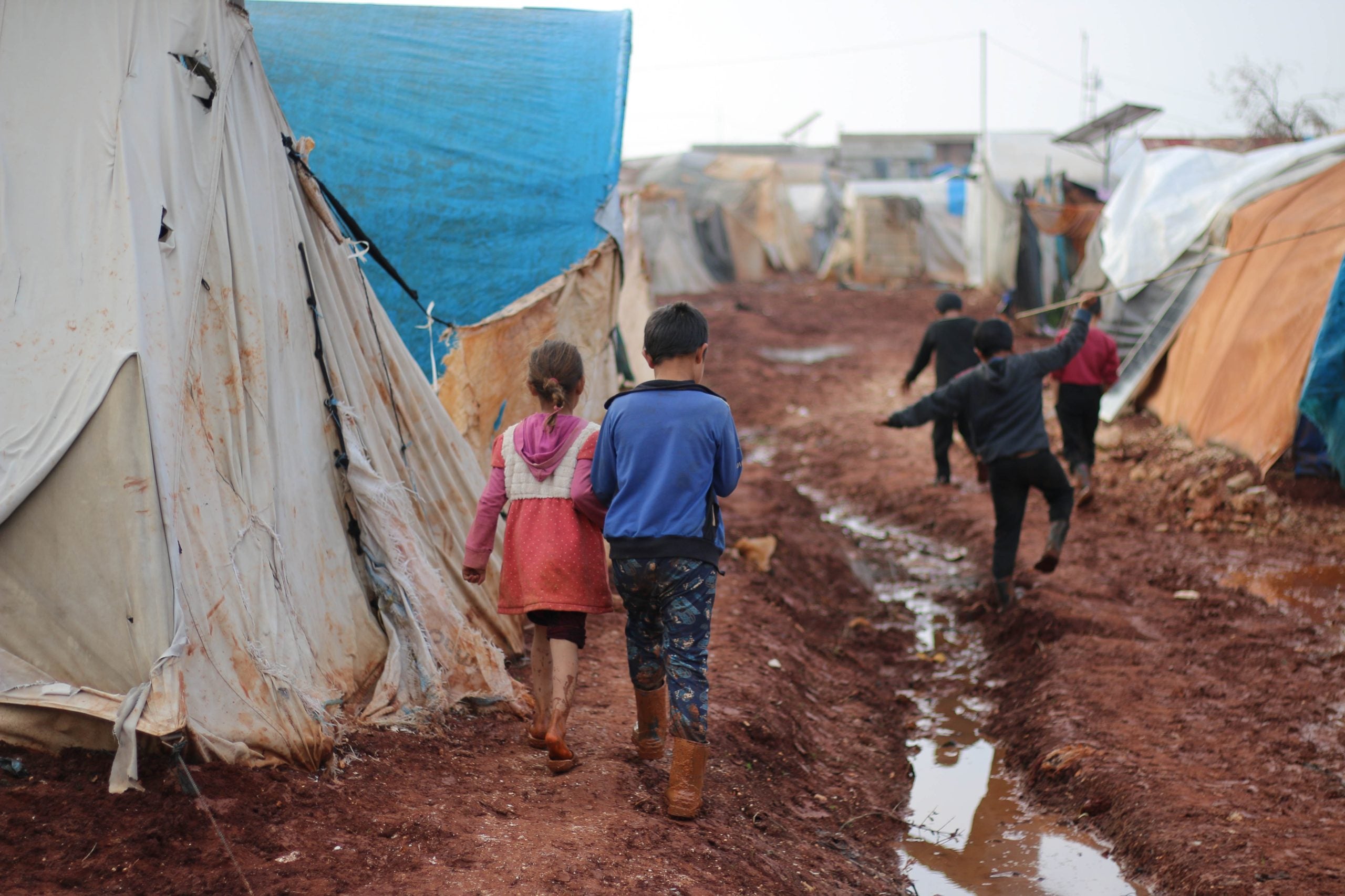 Two refugee children walking through a camp. SOURCE: Pexels