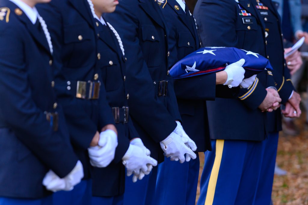 Servicemembers standing with a folded American flag