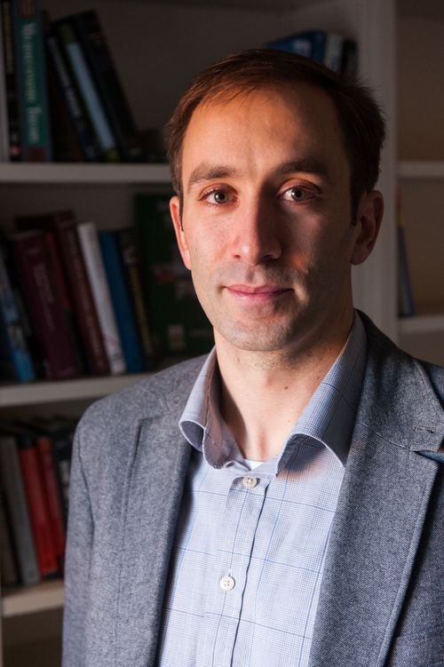 Headshot of Andrew Zeitlin in front of a bookshelf.