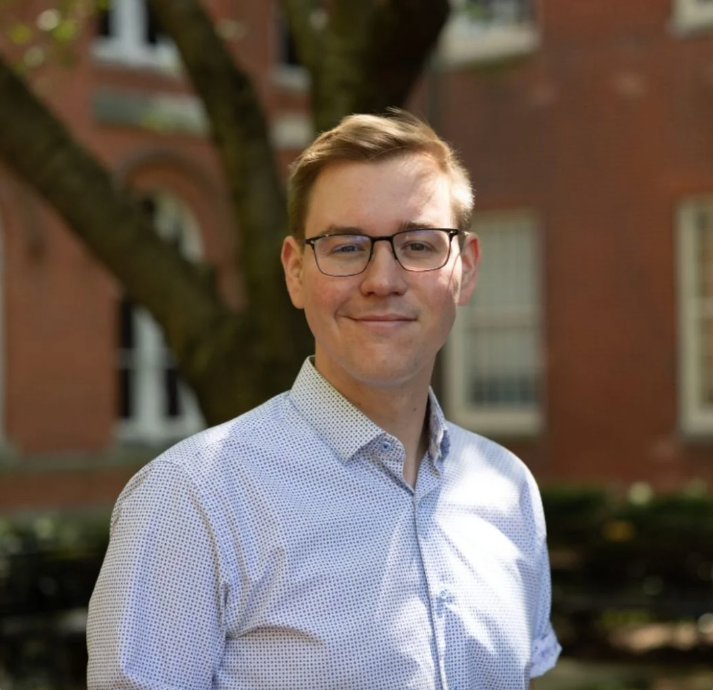 Headshot of Phil Cork in front of a building and a tree