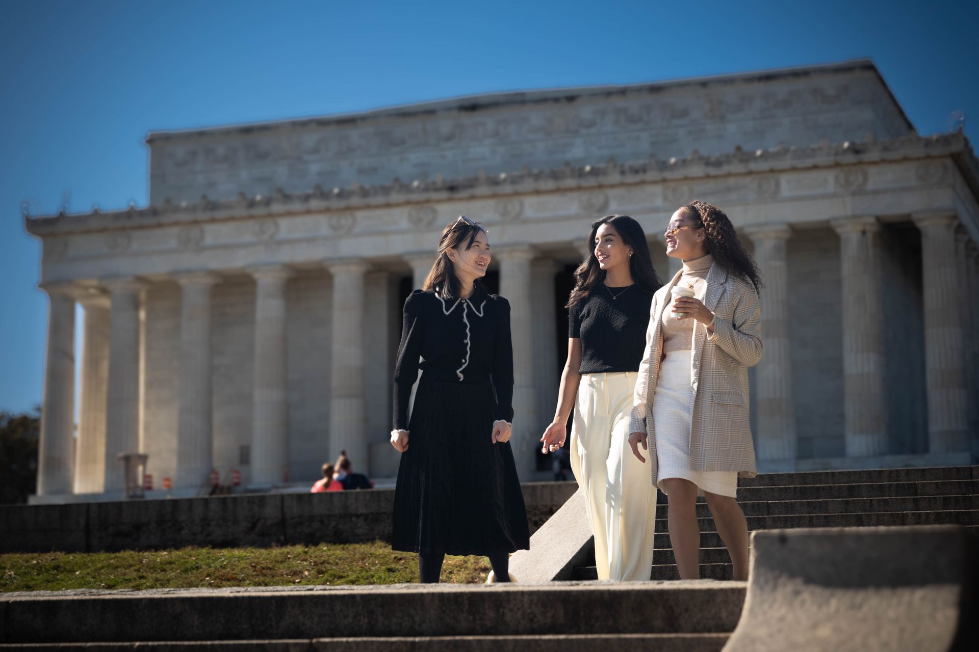 three students talking in front of the Lincoln Memorial