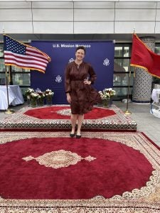 Maggie Sullivan pictured in front of American and Moroccan flags during her time working at the U.S. Mission for Morocco