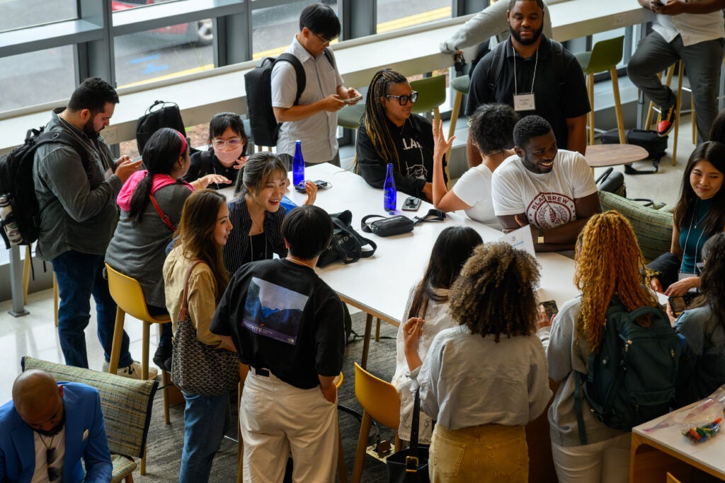 Large group of McCourt Policy students gathered in the student lounge chatting, smiling, and laughing 