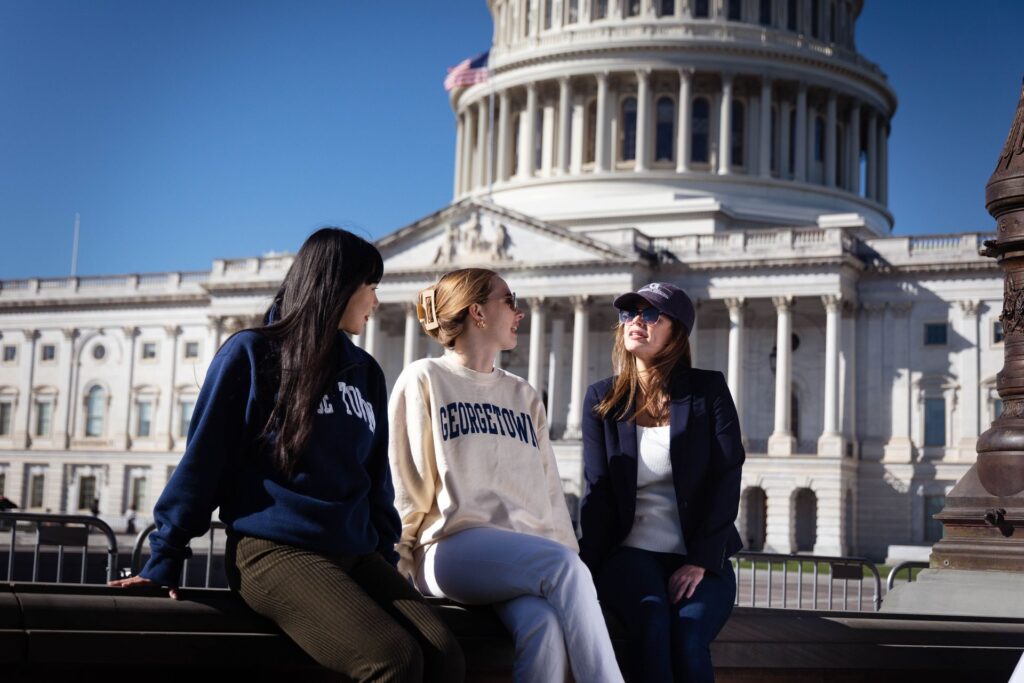three students sitting and talking outside of the US Capitol Building