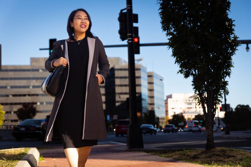 a student walking down the street in Washington DC wearing a dark overcoat and dress.