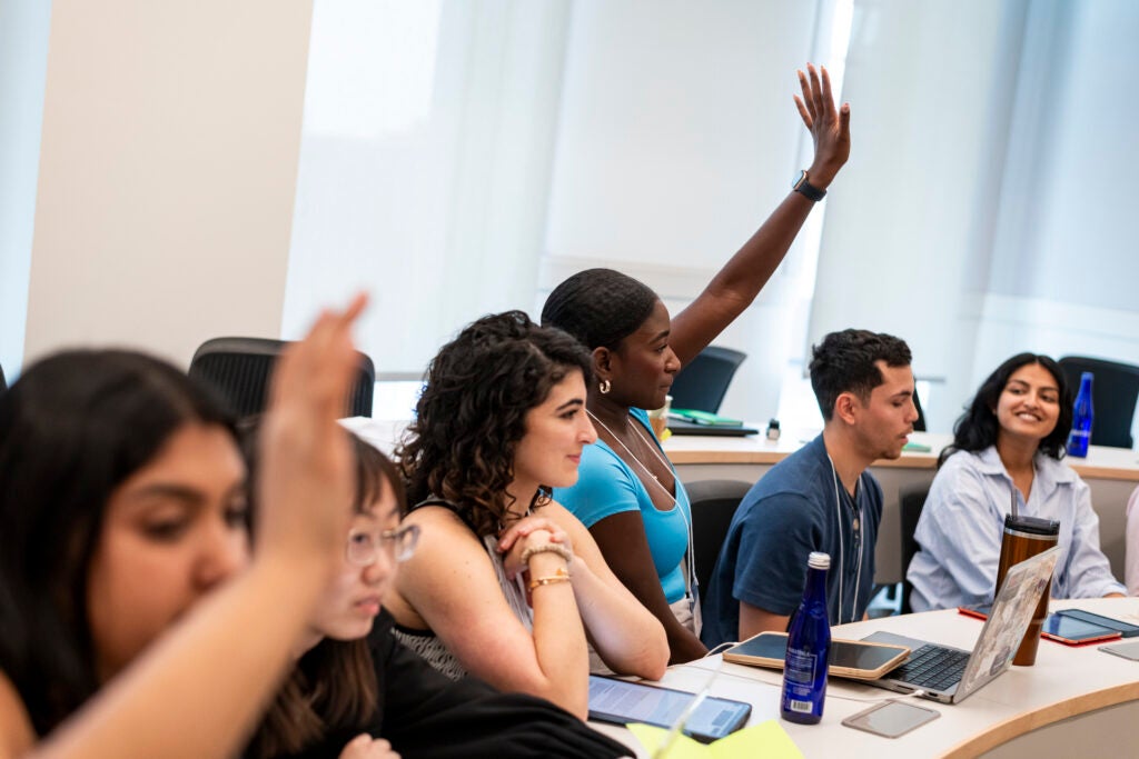 Students raising their hands in a 125 E classroom.