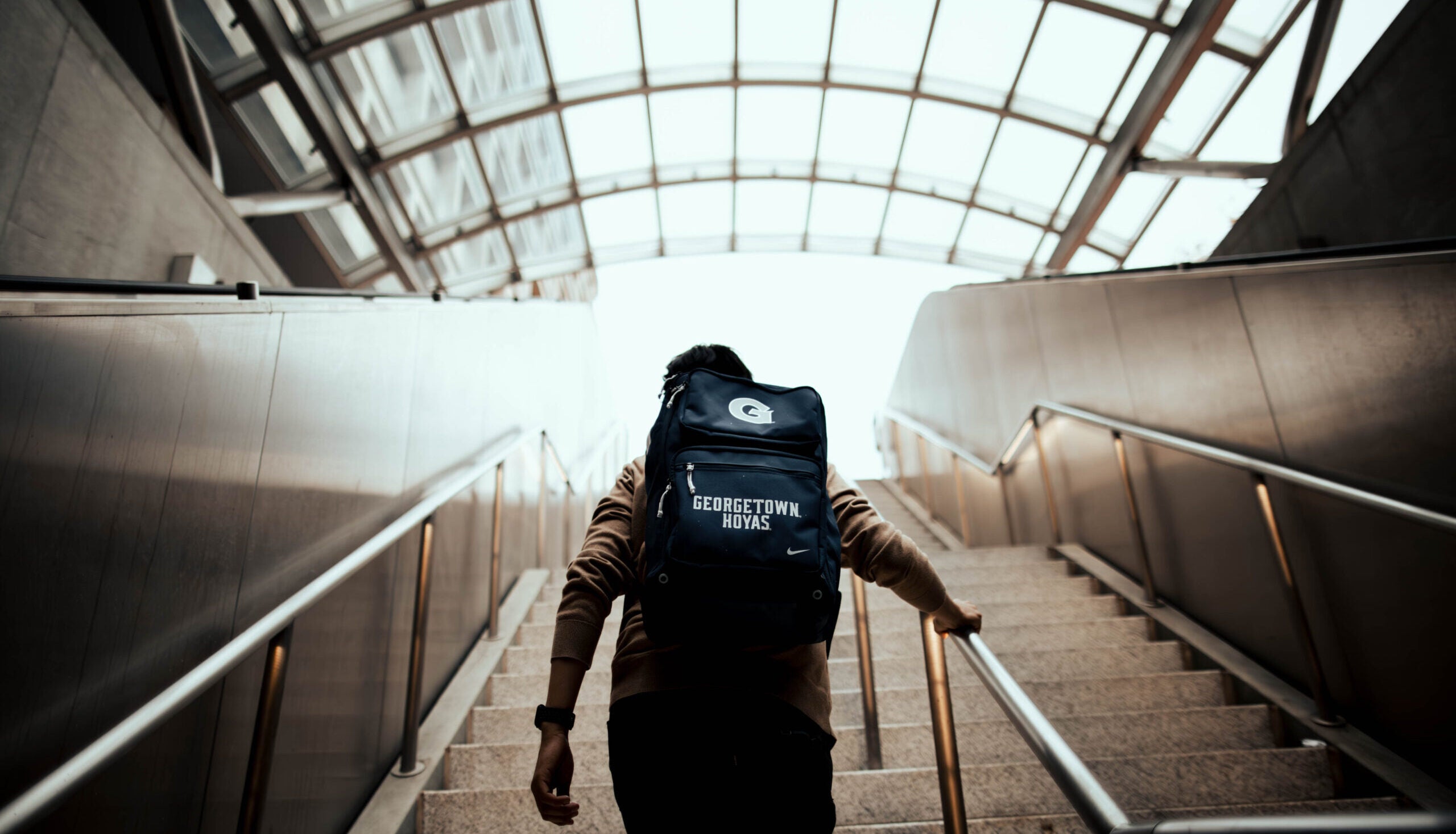 Student walking up the stairs wearing a Georgetown Hoyas backpack