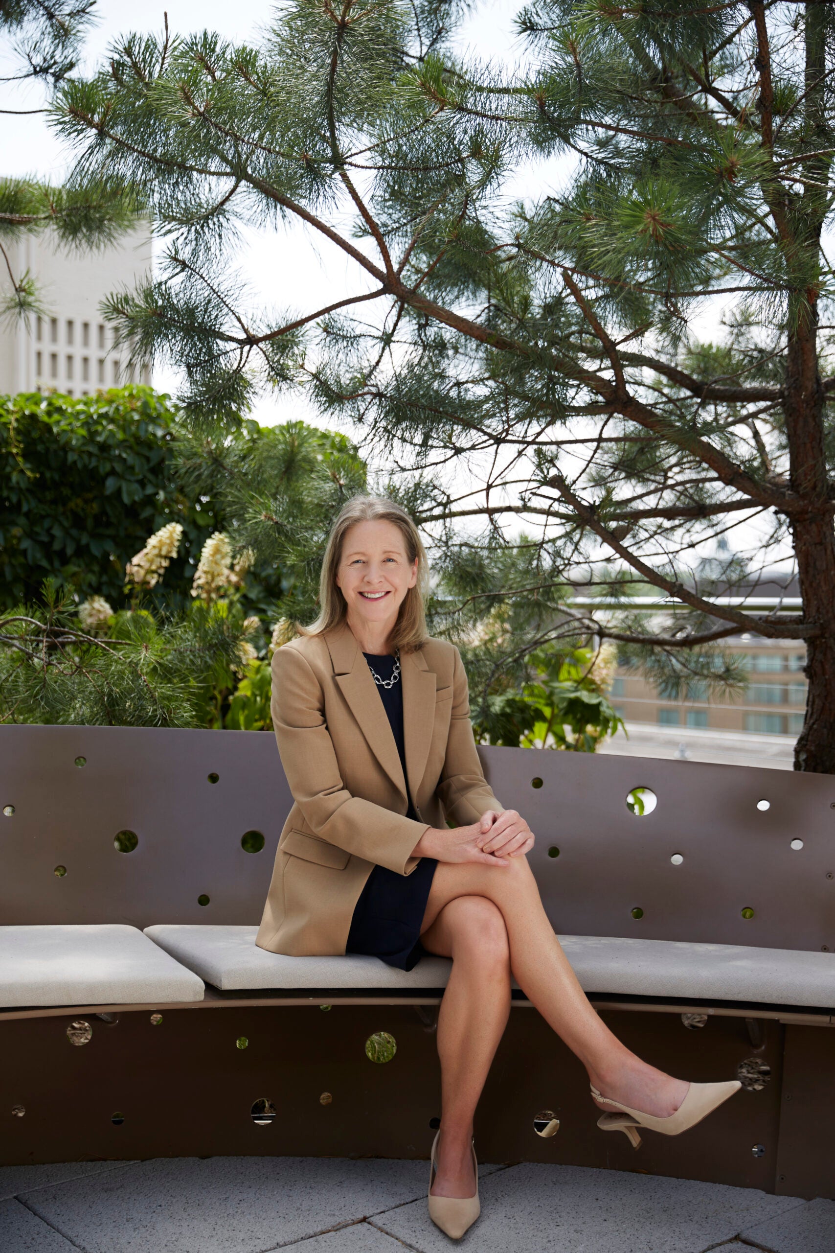 Dean Carole sits legs-crossed in the outside garden on the 9th floor of the McCourt School