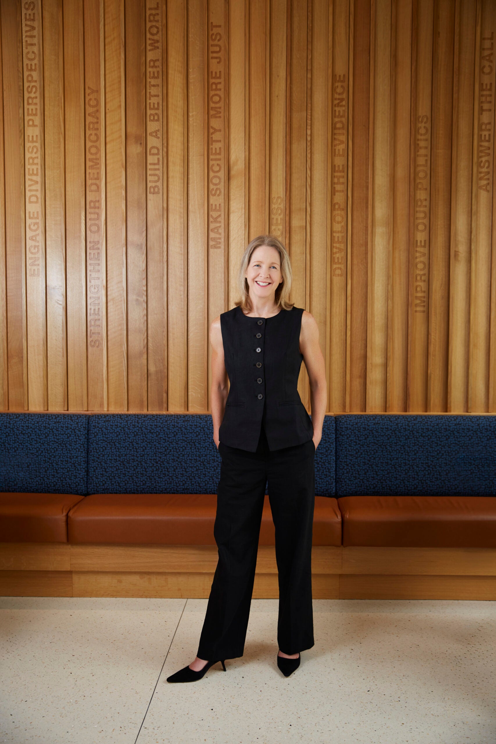 Dean Carole stands in McCourt lobby with hands in pocket