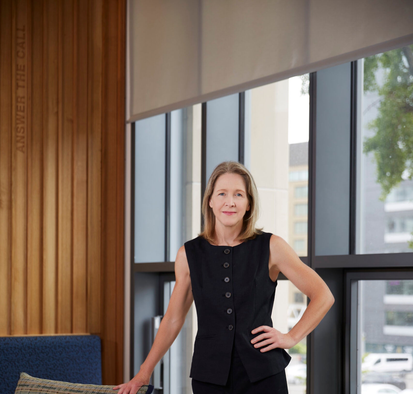 Dean Carole stands leaning against a chair in the McCourt School lobby