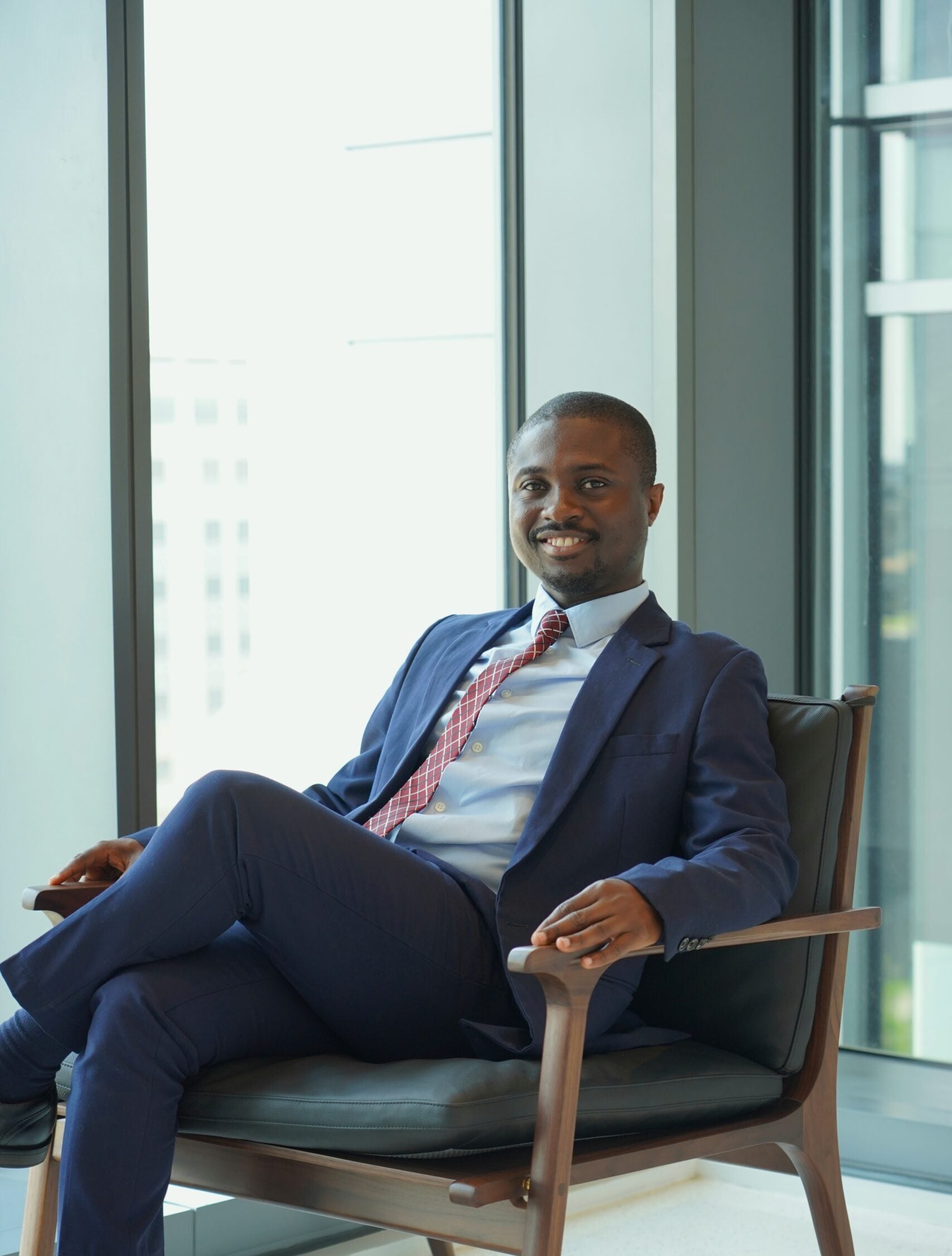 Mensah posed sitting in front of a brightly lit window