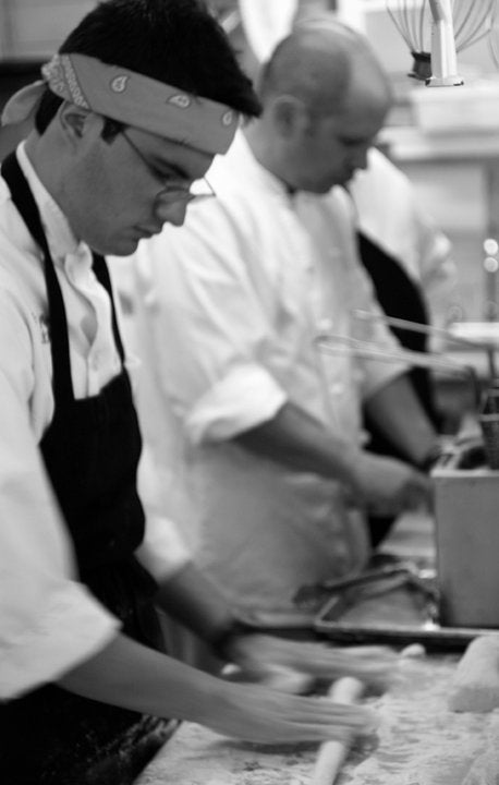 Chefs working the line of a kitchen, Eric Jeffay in the foreground rolling out dough.