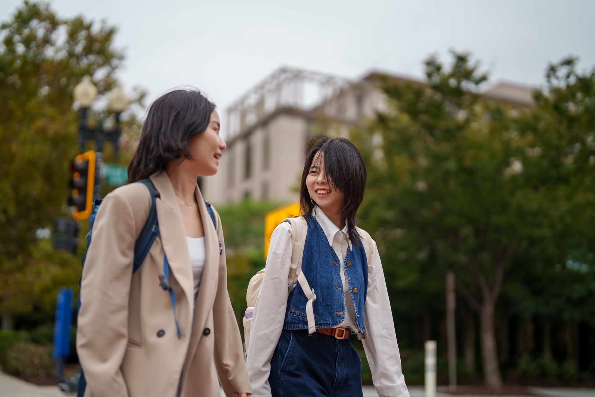 Two students walking together outside and talking.