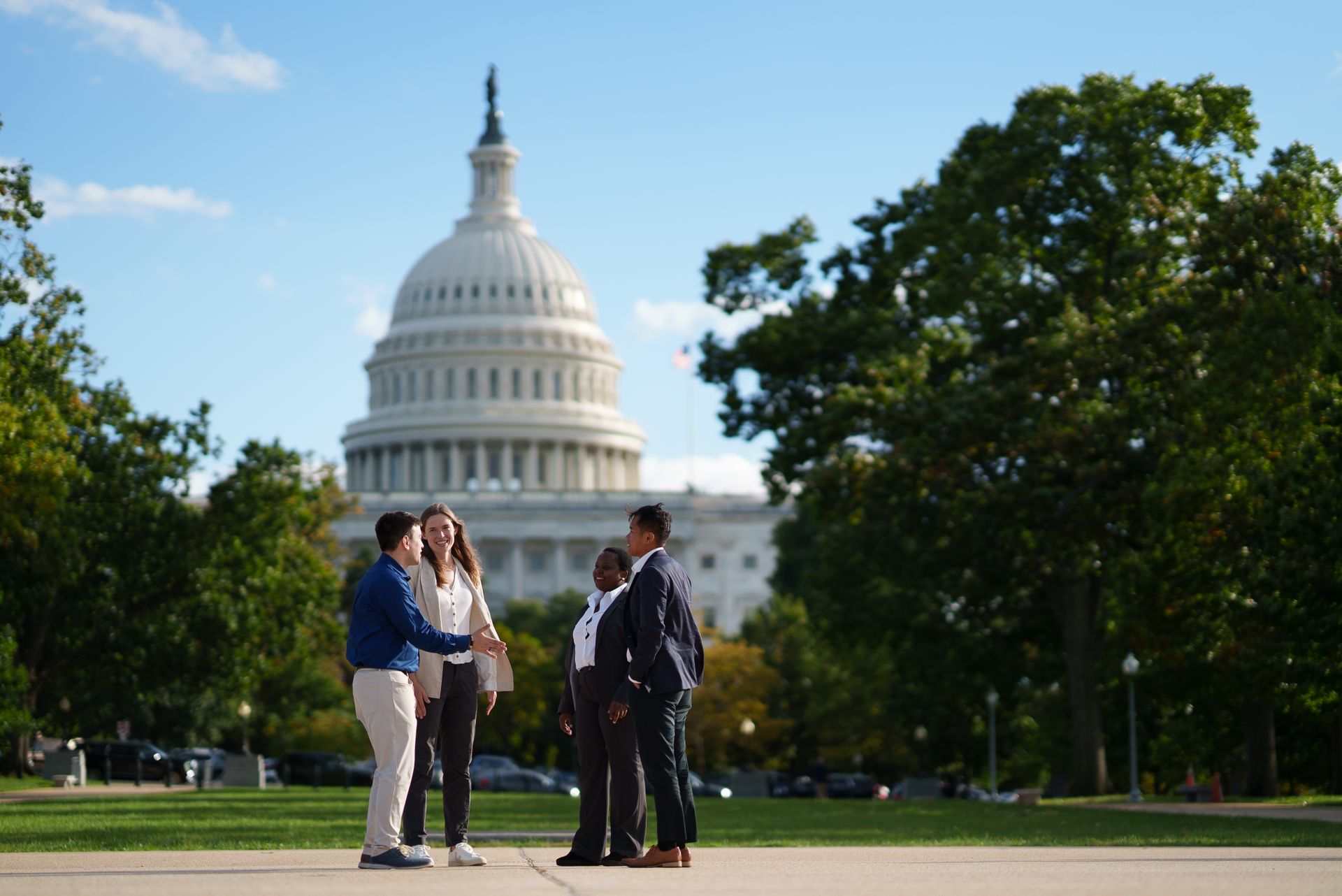 Four students talking together in front of the US Capitol building.