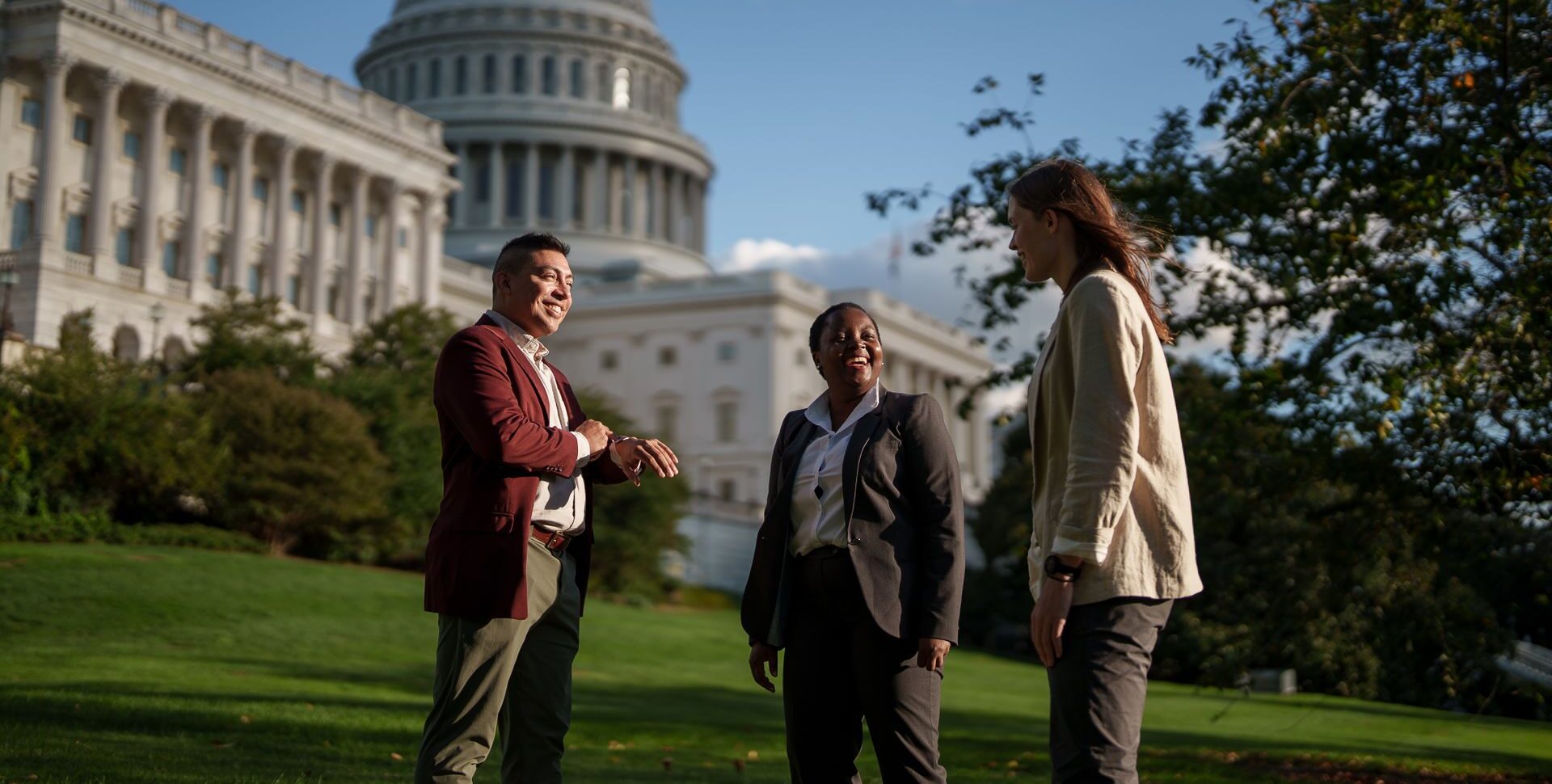 Three students talking together in front of the US Capitol building.
