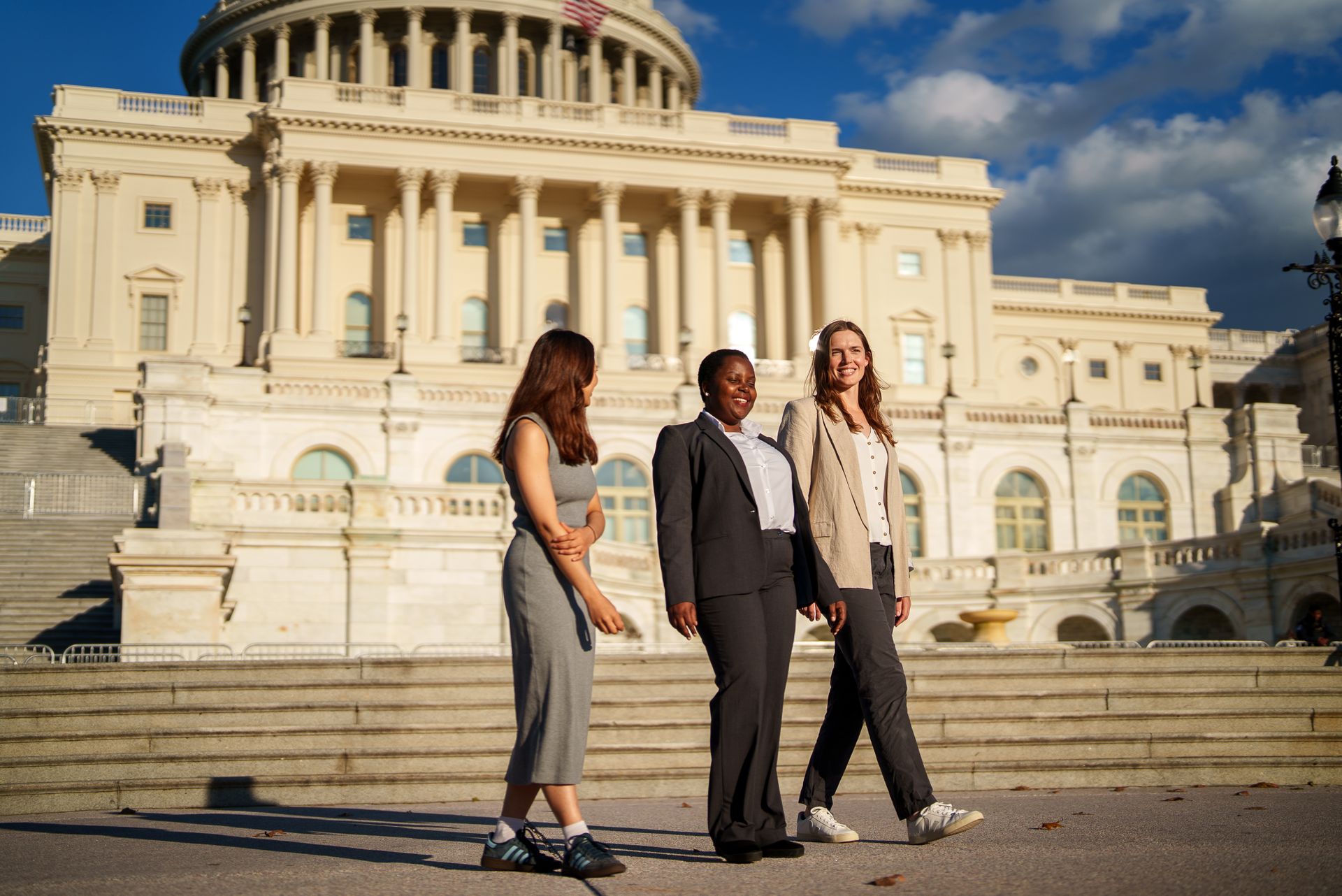 Three students walking together in front of the US Capitol building.