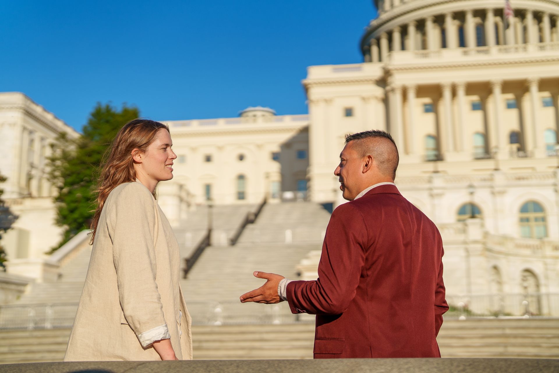 Two students talking together in front of the US Capitol building.