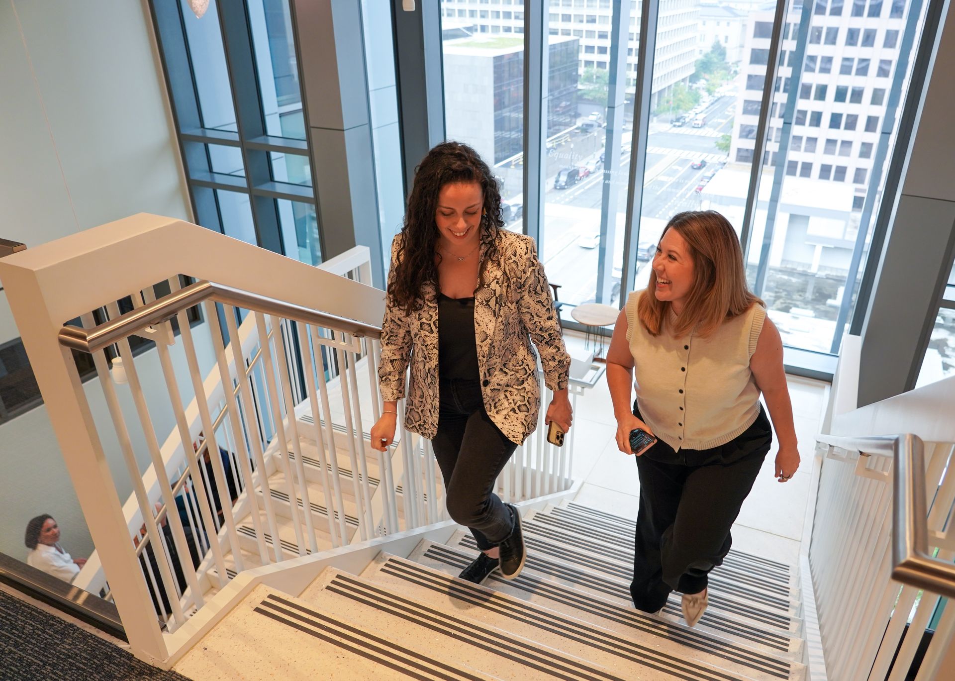 Two students walking up stairs together and laughing.
