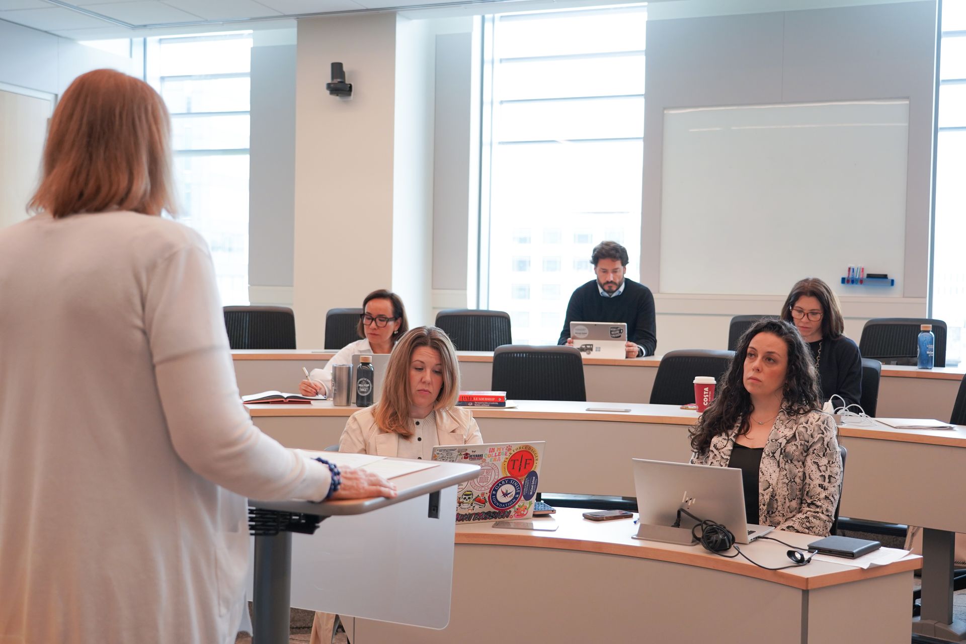 Five students listening to an instructor speaking in class.