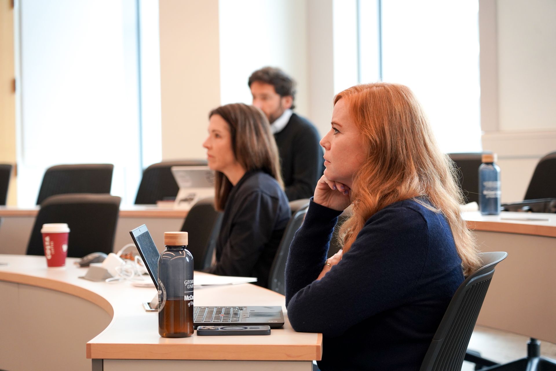 Three students listen intently in class.