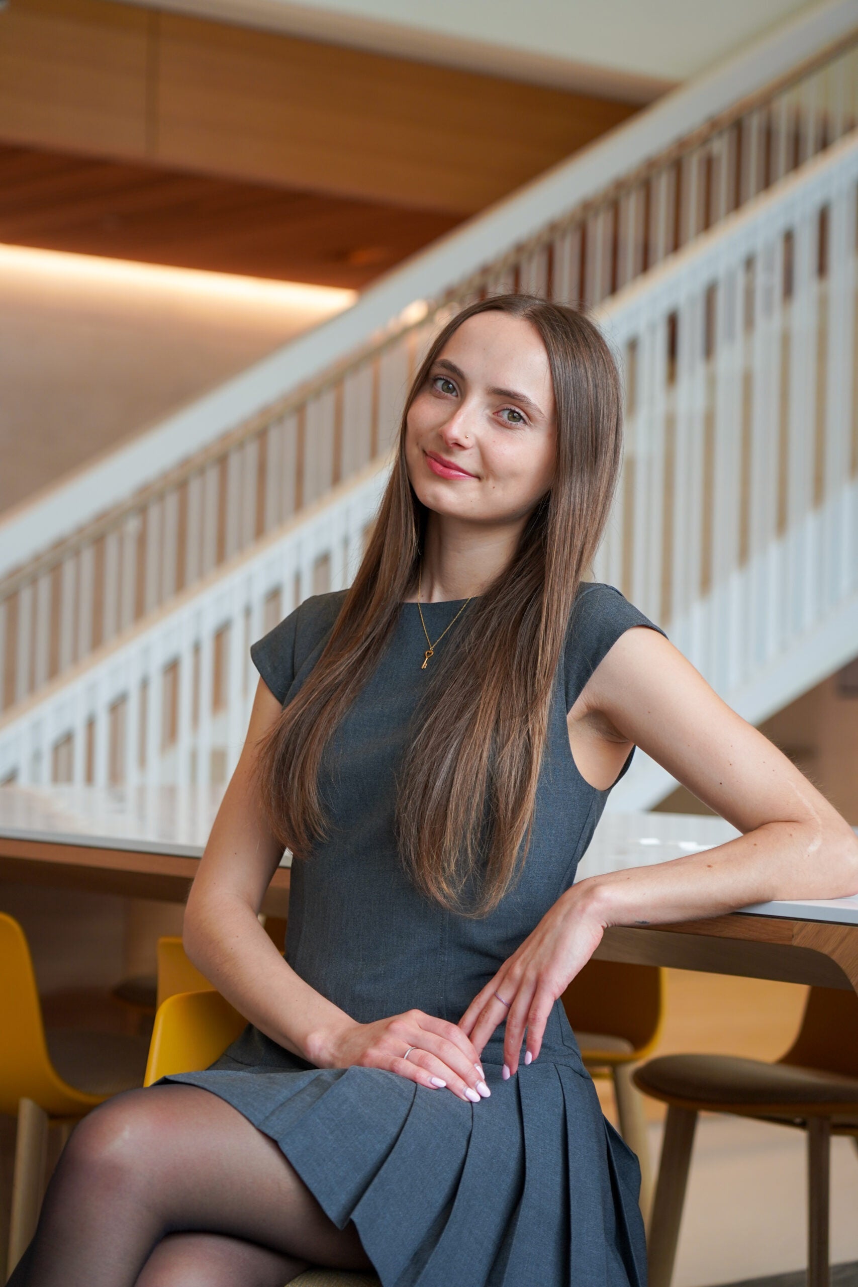 A woman (Camilla Feeley) sits in a dark grey dress