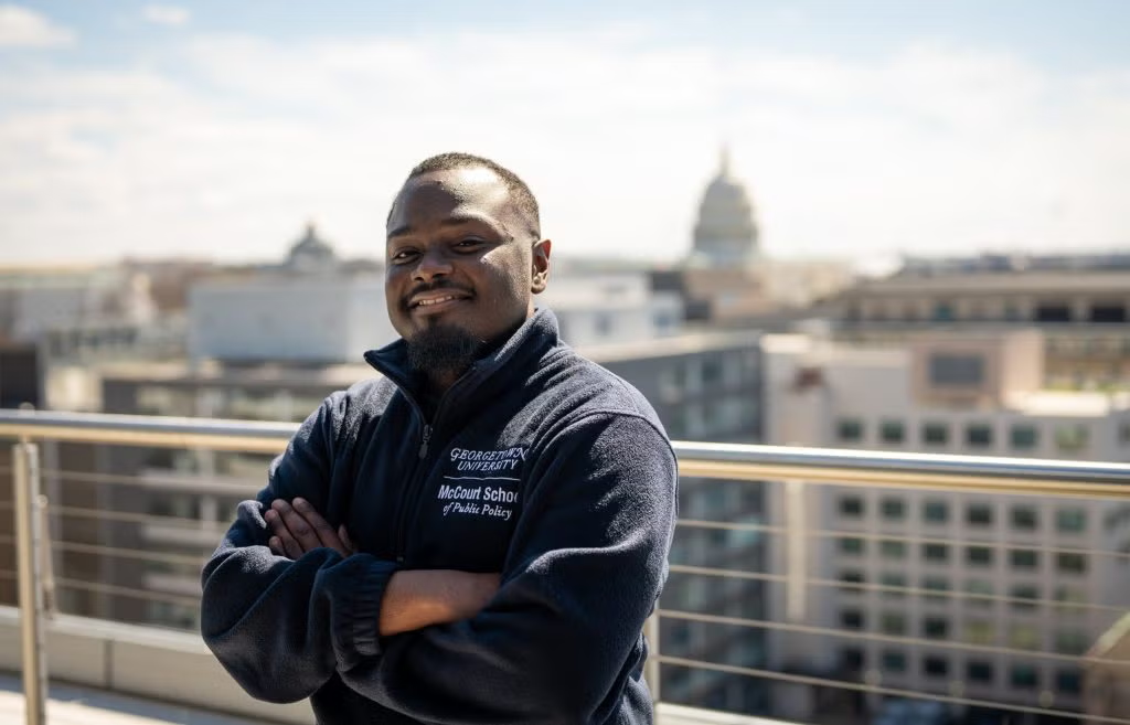 Christopher Edwards stands on the McCourt rooftop, US Capitol in the distance