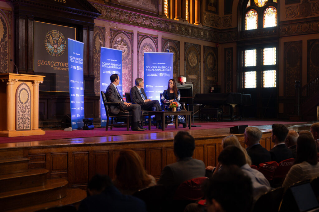 Three people speaking on elevated stage