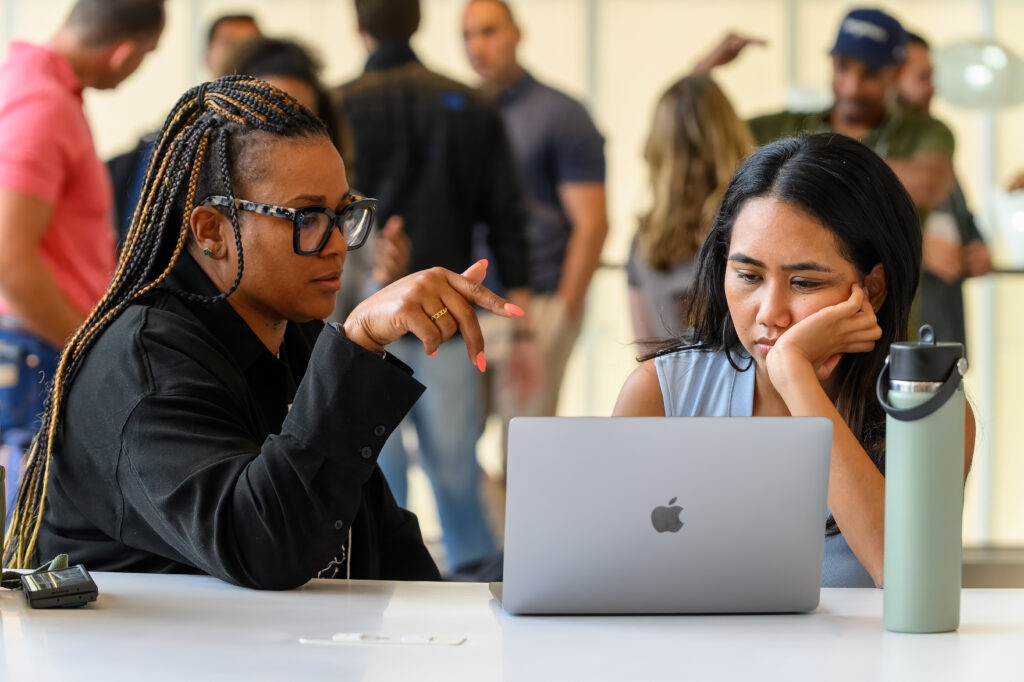 One person helping another with difficult problem on laptop screen