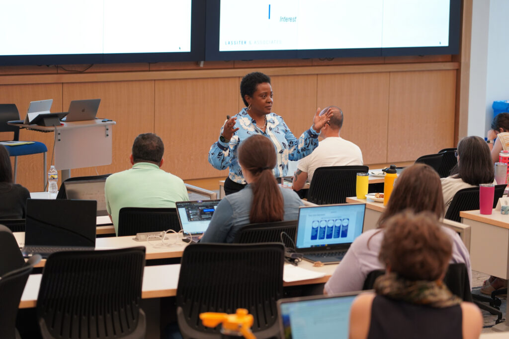 Woman leads lecture from the front of auditorium