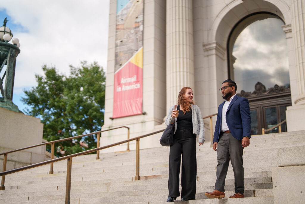 Two professionally-dressed people walking down large staircase.