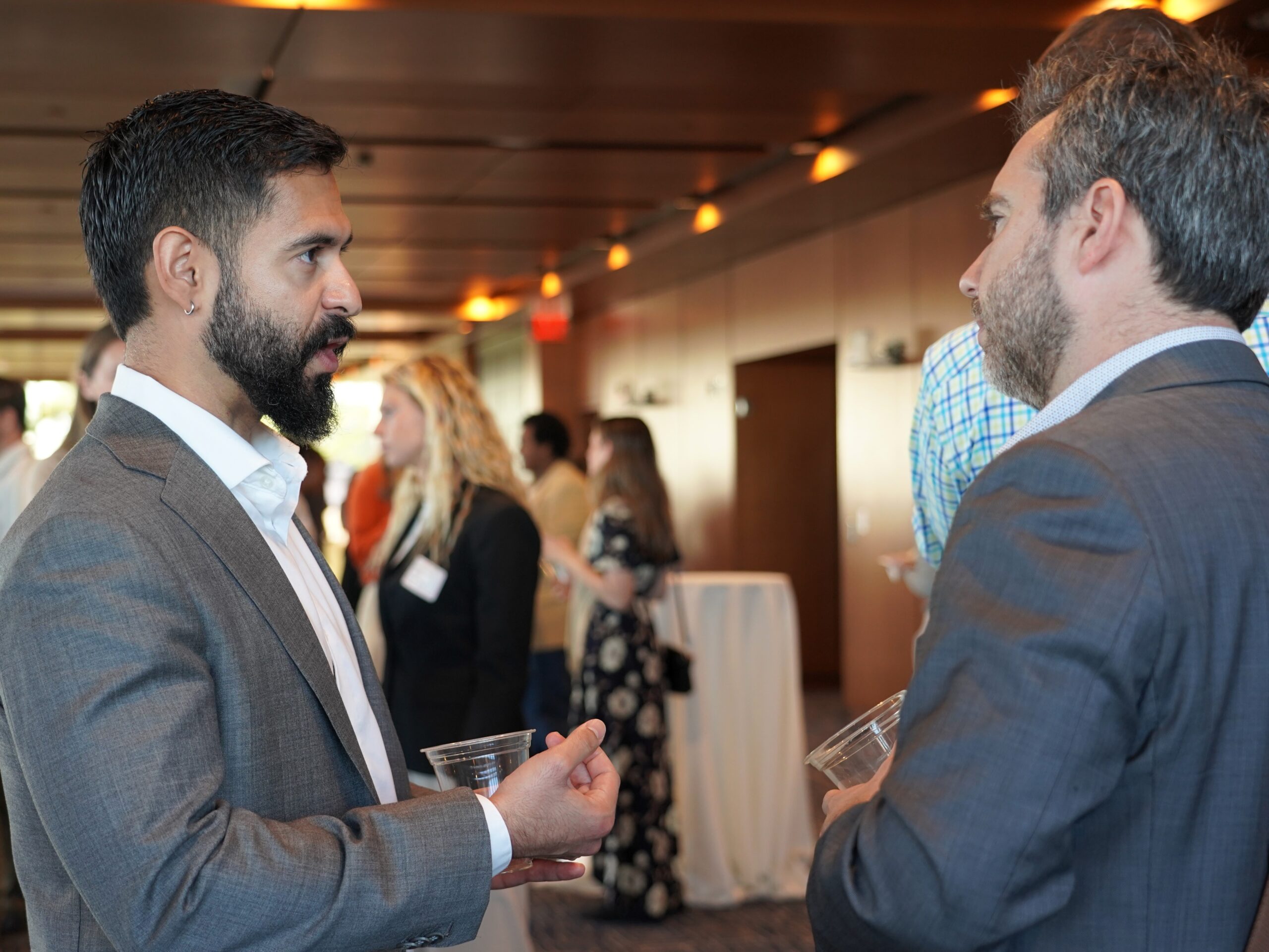 Two individuals speaking to one another, both wearing suits