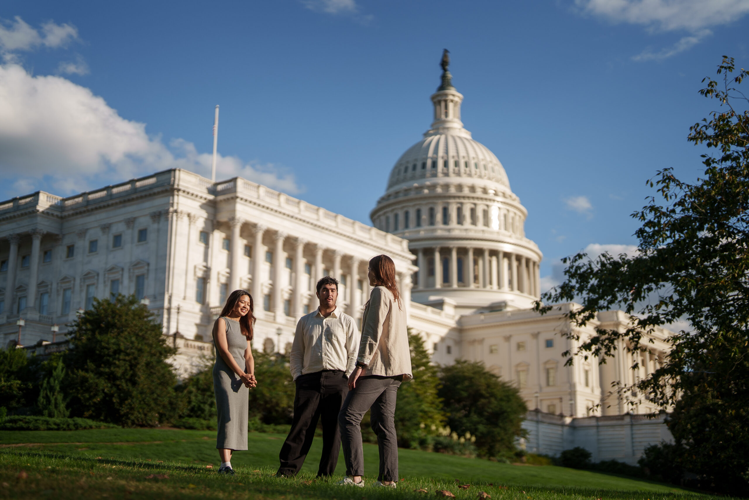 Three people standing around talking in front of the U.S. Capitol