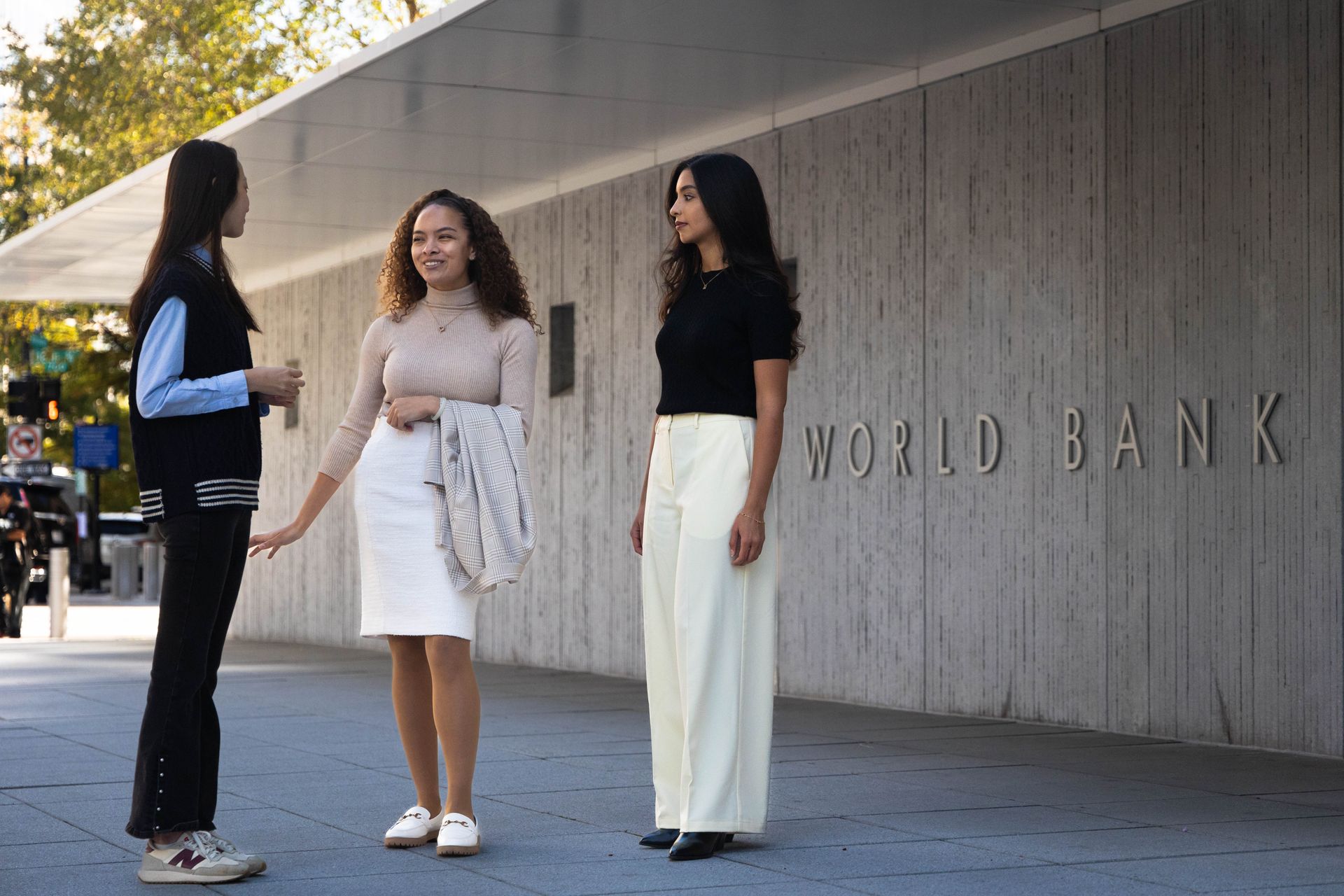 Three people standing out front of the World Bank headquarters