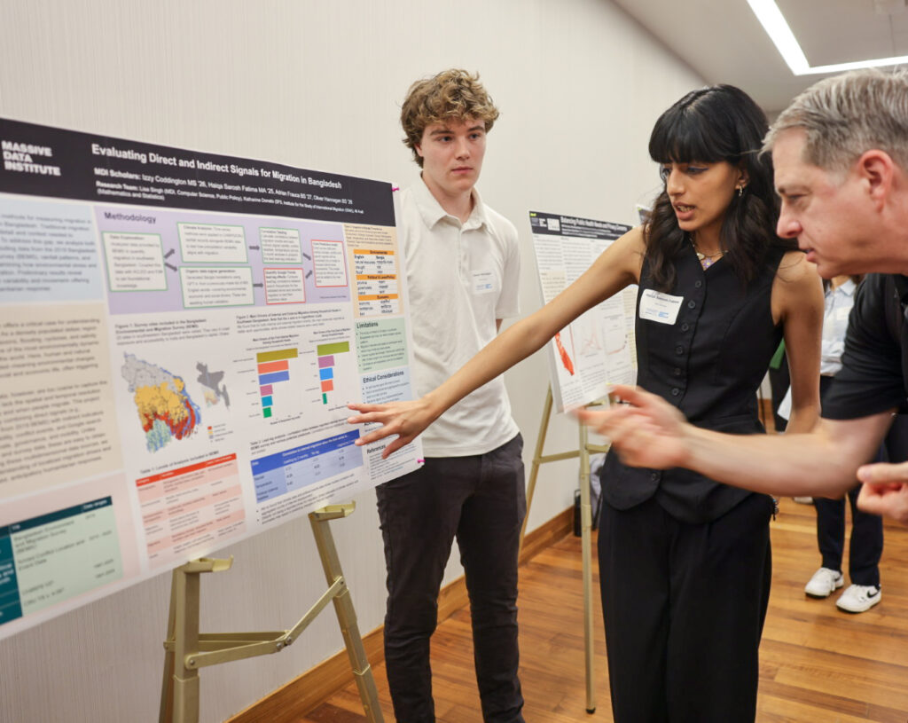 Two people gesturing toward scientific poster