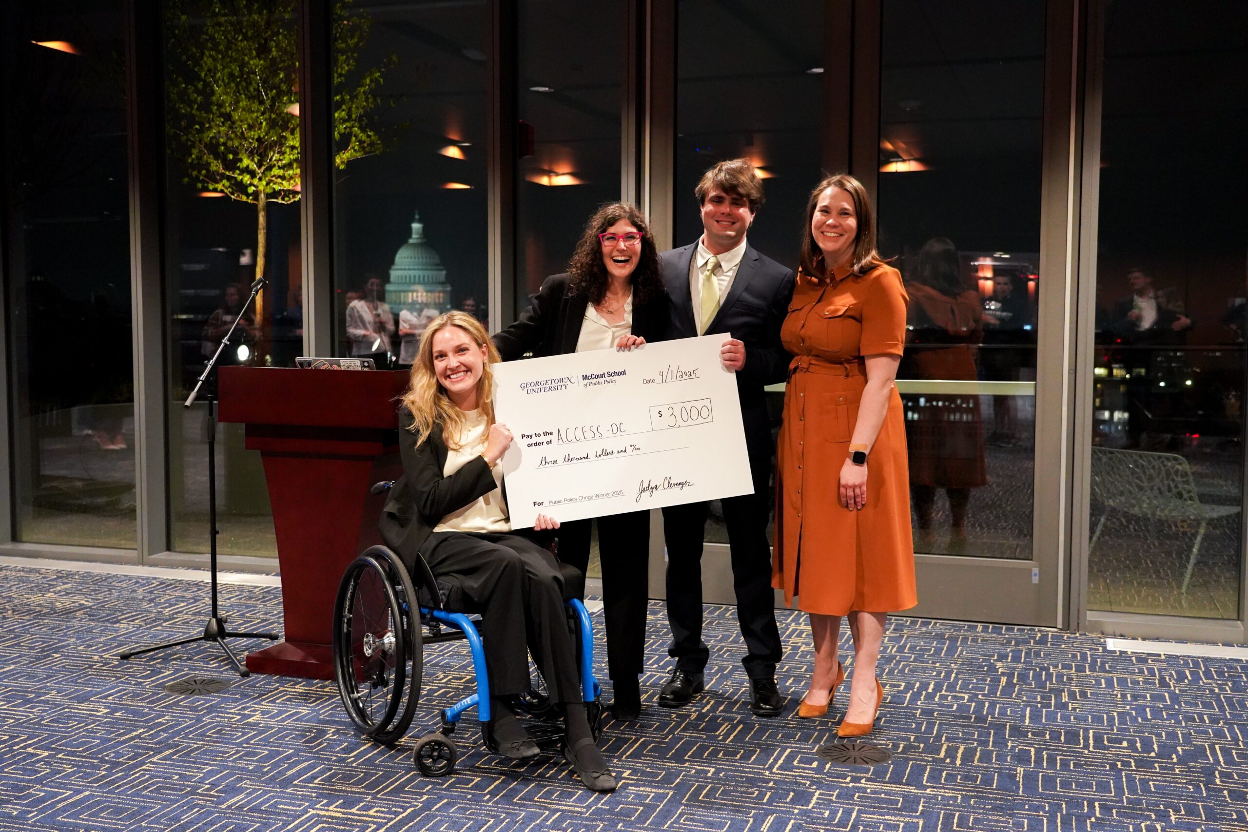 Three McCourt students receiving oversized cheque from McCourt staff member