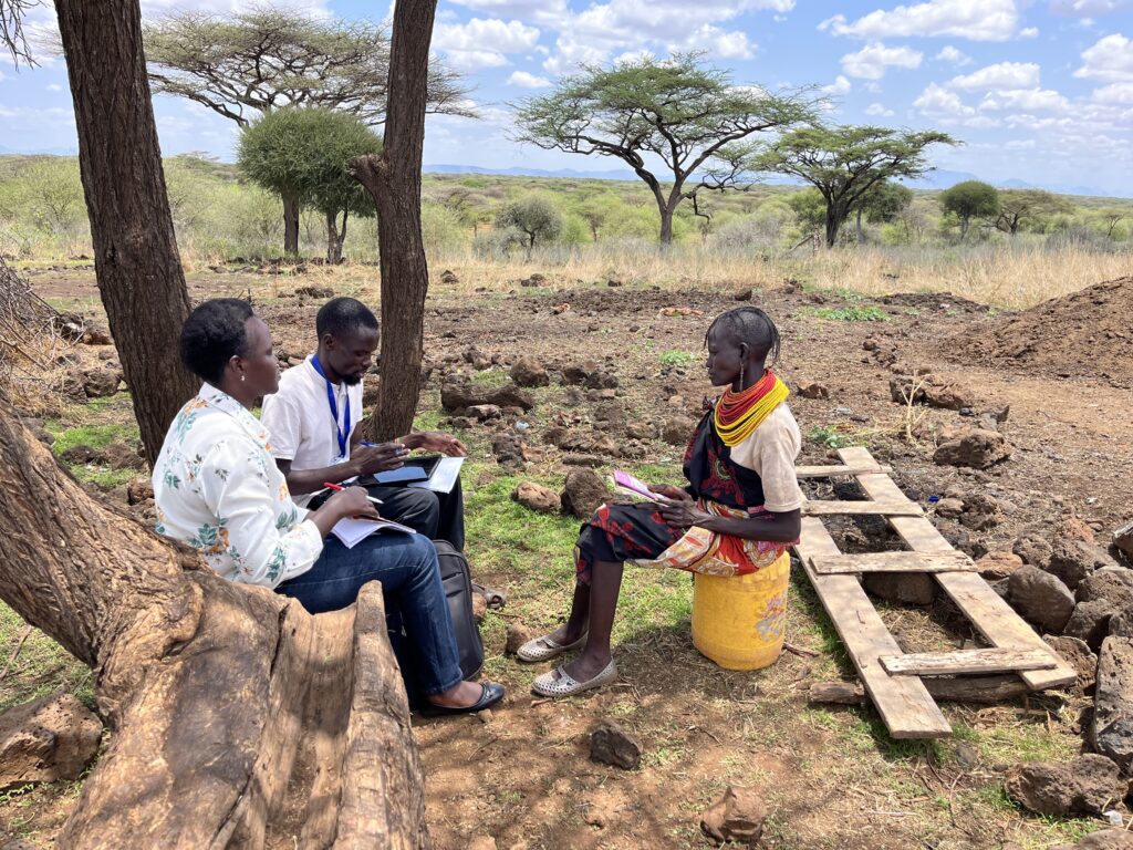 Two people interviewing a third in rural Africa