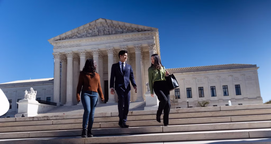 Three students walking down the steps of the Supreme Court