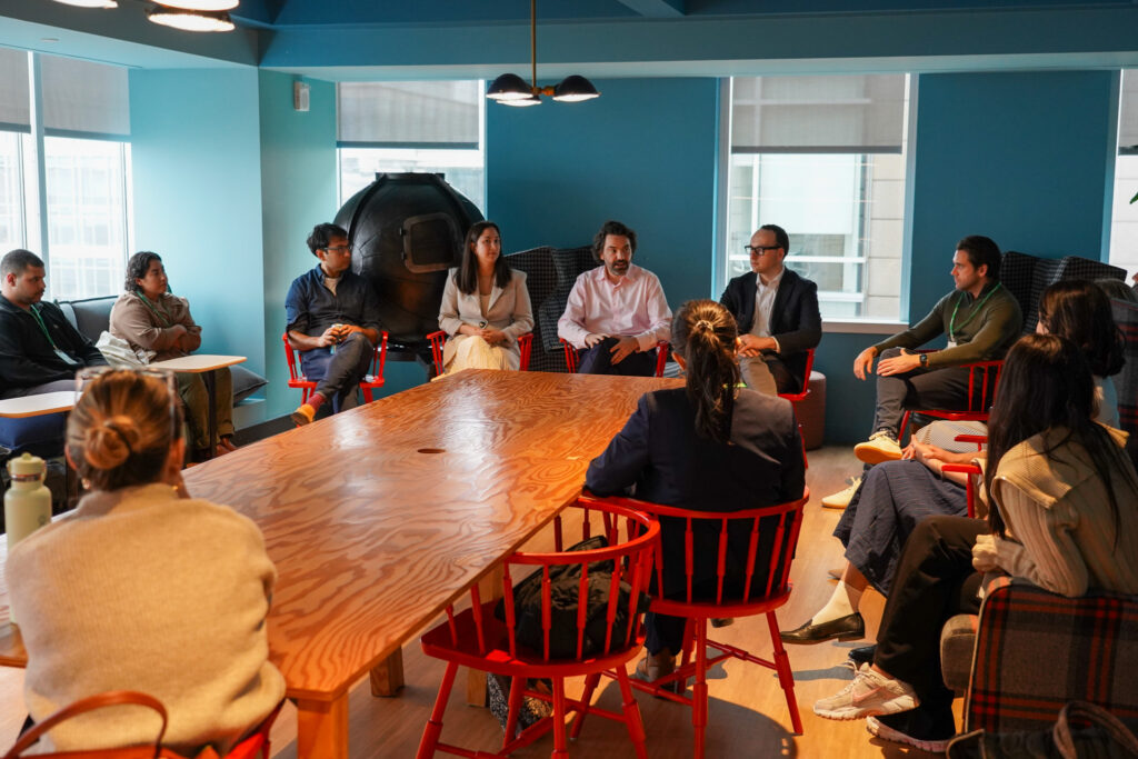 Large group of about twenty people discussing around table