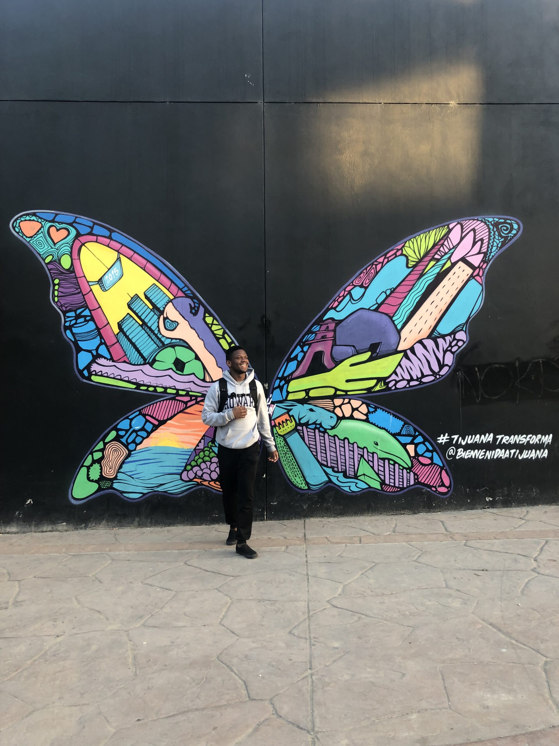 Marlon Brooks stands before butterfly mural