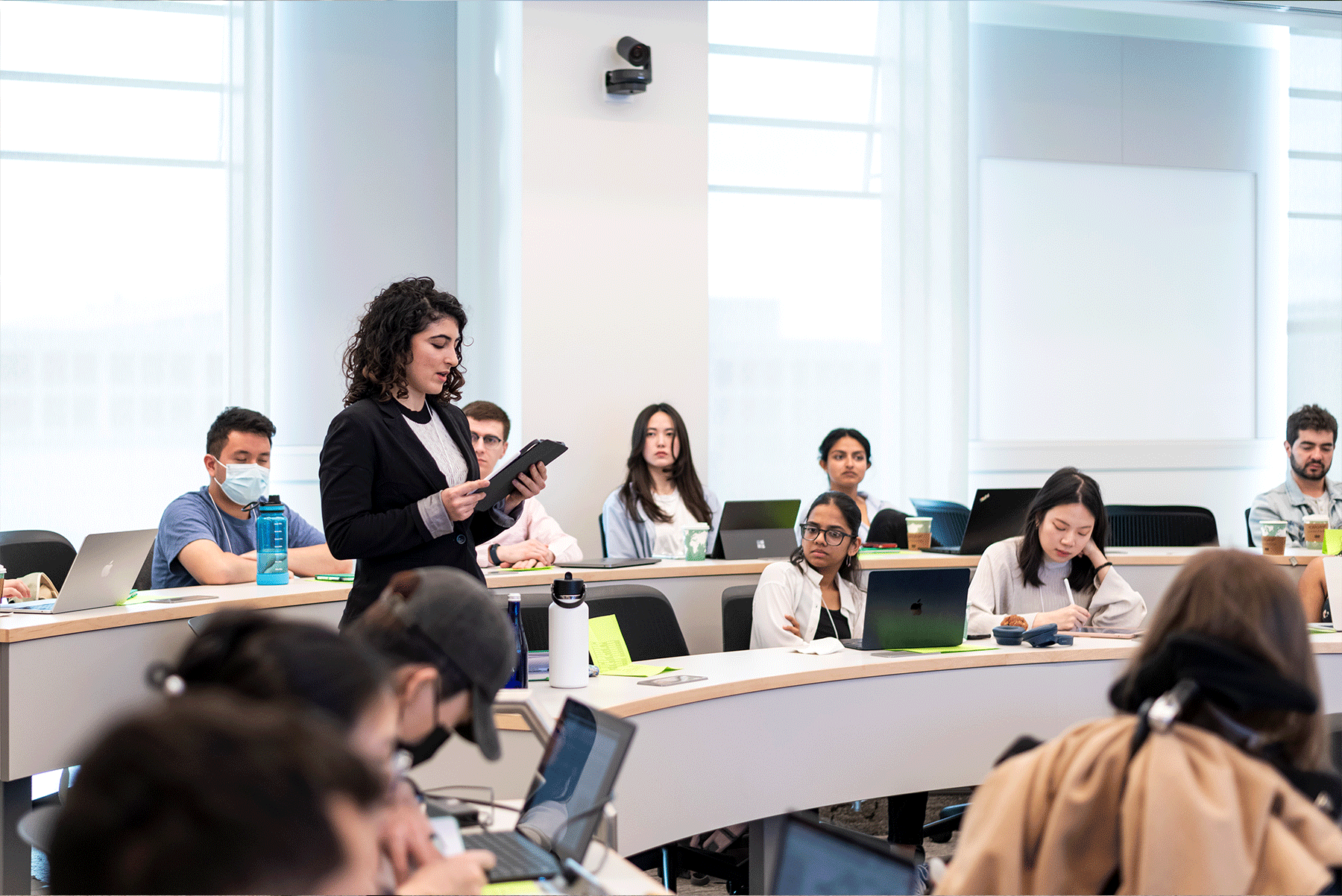 A young woman reads from a tablet in a classroom