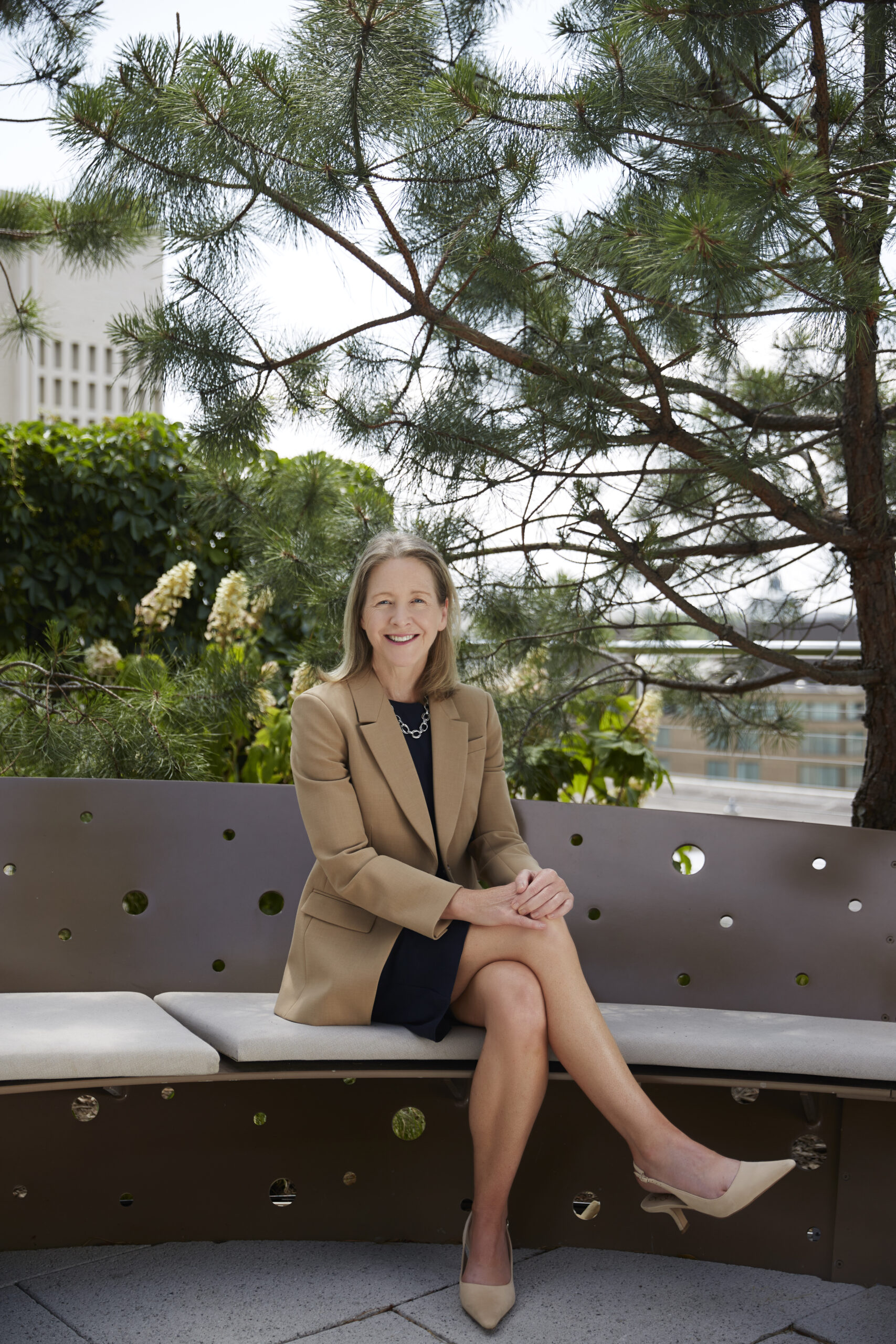 Dean Carole sits legs-crossed in the outside garden on the 9th floor of the McCourt School