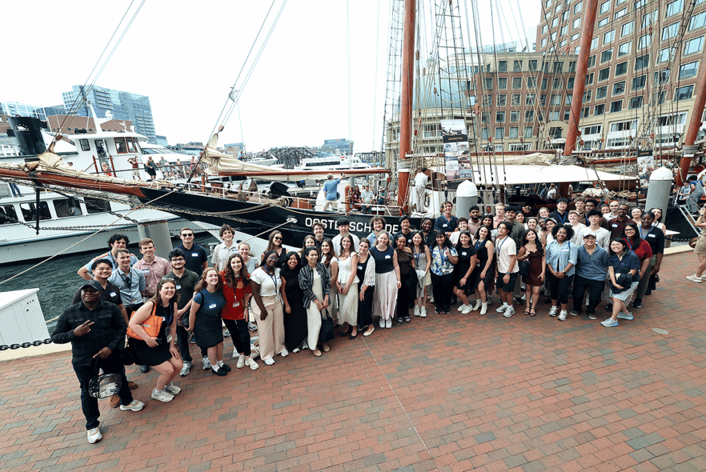 Large group of people in front of old sail boat