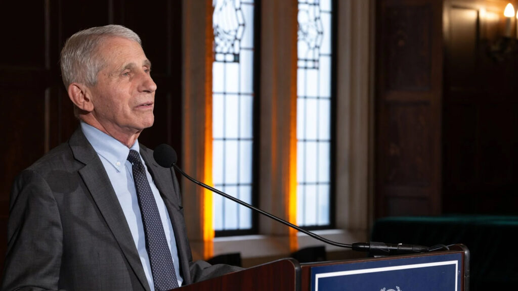 Dr. Fauci presents from lectern, seen in profile